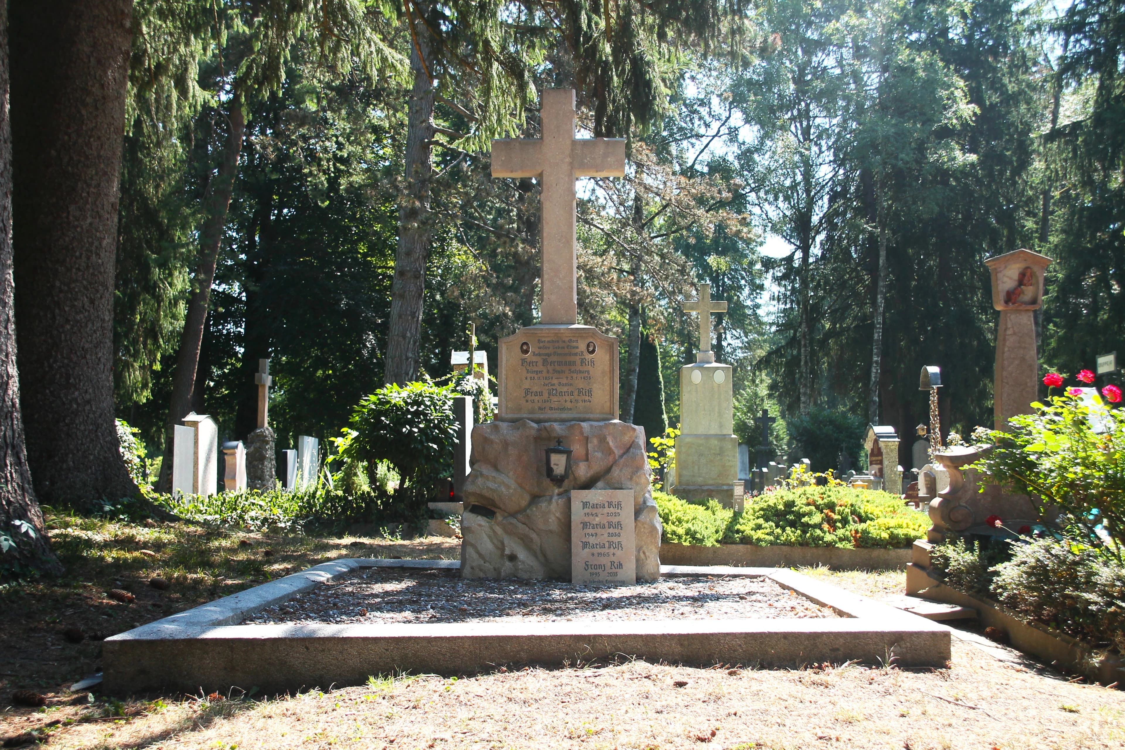 Moriva-Mitarbeiter bei der sorgfältigen Pflege eines Grabsteins mit Kreuz, umgeben von Blumen